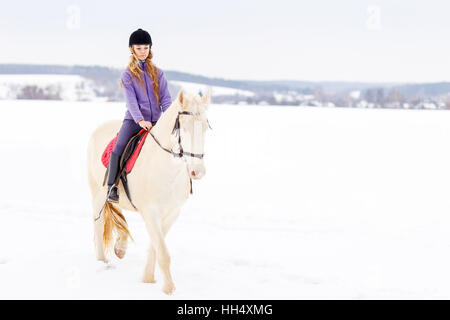 Jeune fille à cheval blanc équitation casque sur terrain Banque D'Images