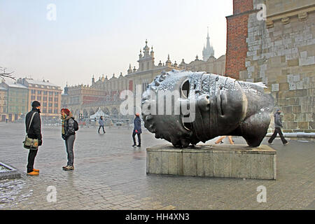 Cracovie, Pologne - 4 janvier 2011 : sculpture tête Eros Bendato sur place du marché par l'artiste polonais Igor Mitoraj avec Sukiennice halle aux draps on background Banque D'Images