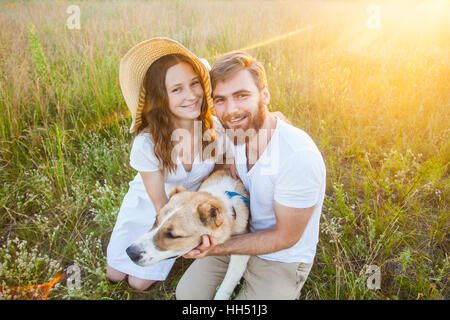 Beau couple heureux avec leur chien Alabai dans la nature avec le coucher du soleil. Banque D'Images
