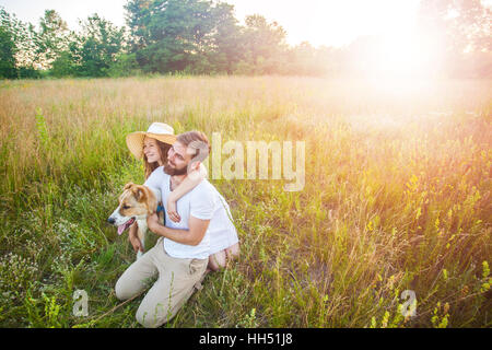 Beau couple heureux avec leur chien Alabai dans la nature avec le coucher du soleil. Banque D'Images
