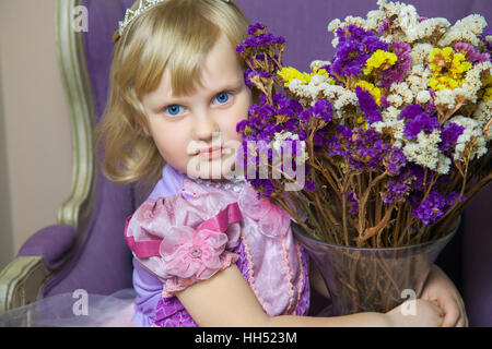 Peu heureux princess fille en robe rose et couronne dans son prix pose et souriant. Banque D'Images