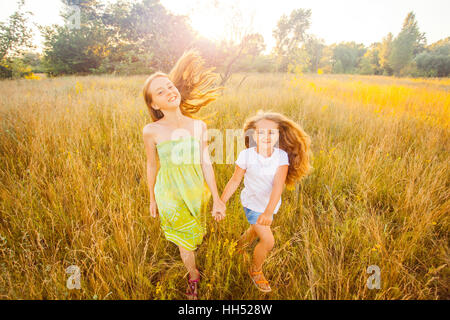 Deux belles sœurs s'exécutant sur la pelouse dans le parc naturel de l'outdoor en été. La liberté et l'insouciance. Enfance heureuse. Banque D'Images