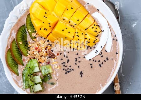Smoothie chocolat bol avec kiwi, mangue et granola. L'amour pour la santé de l'aliment cru concept. Banque D'Images