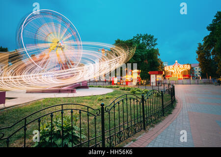 Les effets de flou de mouvement autour de la haute vitesse en fonction de l'Attraction lumineuse rotative City Amusement Park. Grande Roue sur soir d'été, ciel bleu Bac Banque D'Images