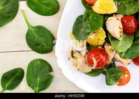 Garni de salade Feta couper des épinards, poulet, tomates cerise et orange on white plate Banque D'Images