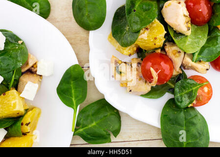 Garni de salade Feta couper des épinards, poulet, tomates cerise et orange on white plate Banque D'Images