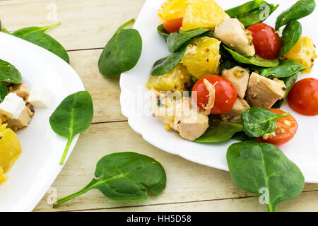 Garni de salade Feta couper des épinards, poulet, tomates cerise et orange on white plate Banque D'Images