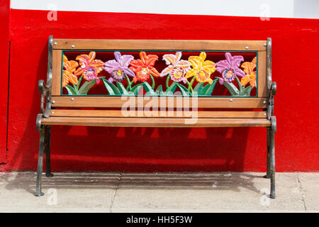 Banc coloré avec motifs floraux contre un mur rouge, El Jardin Colombie Banque D'Images