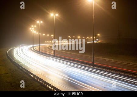 Vue de la route de nuit avec des traces de phares des voitures dans la nuit d'été pluvieux Banque D'Images