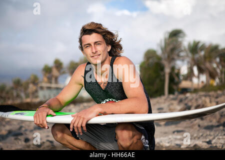 Jeune, souriant tenant une planche de surf sur la plage Banque D'Images