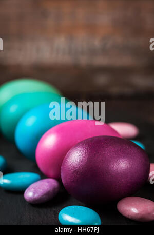 Les oeufs de Pâques peints colorés dans un carton sur fond sombre Banque D'Images