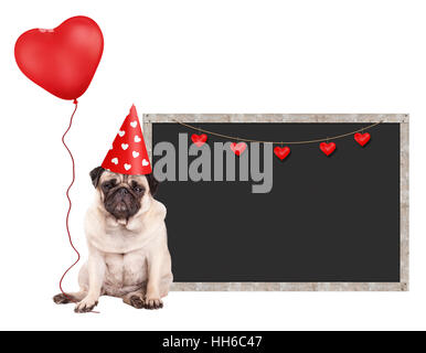 Cute puppy dog pug avec red party hat, assis à côté de blank blackboard signe et holding heart shaped balloon, isolé sur fond blanc Banque D'Images