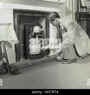 1950, historiques, nouvellement arrivés à l'étranger étudiant indien à l'Institut de l'éducation (OIE) tente d'allumer un feu de gaz pour chauffer une bouilloire à son logis. Banque D'Images