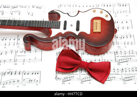 Guitare et noeud papillon sur la feuille de musique imprimée Banque D'Images