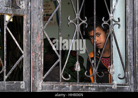 Sanaa, Yémen. 17 Jan, 2017. Un orphelin regarde à travers son habitation porte à l'institution des orphelins gérés par le gouvernement à Sanaa, Yémen, le 17 janvier 2017. Il y a plus de 700 enfants de tous les différents gouvernorats d'orphelins vivant dans les maisons de l'Institution à Sanaa. Les orphelins du Yémen sont durement touchées par la guerre, avec la diminution du financement accordé à un gouvernement et non-gouvernement exécutant des orphelinats à travers le pays, ainsi que de dons de particuliers et d'initiatives s'est tari. Credit : Mohammed Mohammed/Xinhua/Alamy Live News Banque D'Images