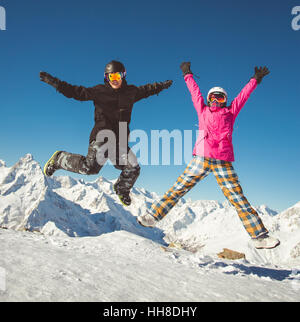Couple heureux de snowboarders sautant dans les montagnes des Alpes Banque D'Images