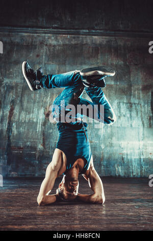 Jeune homme le break dance sur vieux mur arrière-plan. Vintage style film couleurs. Banque D'Images