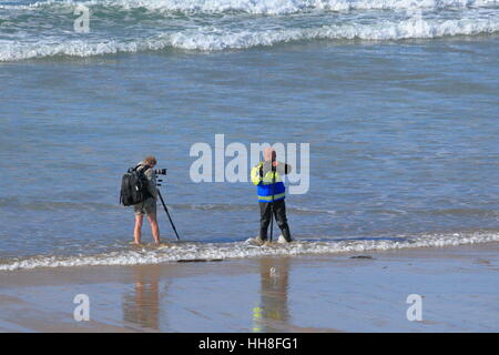 Deux photographes avec des téléobjectifs prêt d'attente sur la plage - pour quelle occasion ? Est-ce que le surf d'un cornish beach le donner ? Banque D'Images