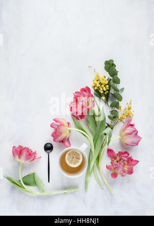 Mise à plat avec des tulipes et de verre disposés sur toile peint blanc et gris en lumière naturelle Banque D'Images