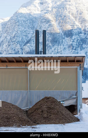 Pile de biocarburants de copeaux de bois en face de la petite centrale électrique de chauffage en montagne prêt à produire l'énergie thermique Banque D'Images