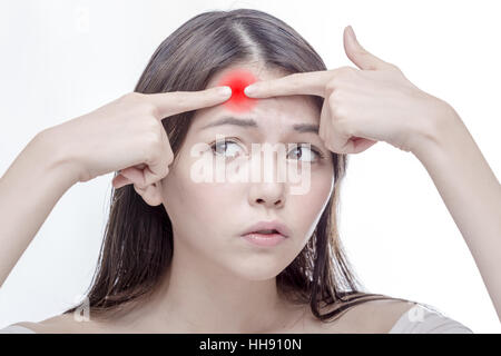 Chinese woman squeezing un point rouge sur son front, désaturé Banque D'Images