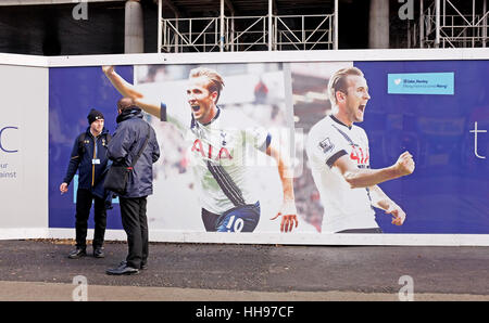 Les hommes à discuter l'un fumer une cigarette à l'extérieur du stade de White Hart Lane nouvelle construction de Tottenham Hotspur FC avec des affiches de Harry Kane Banque D'Images