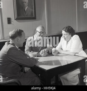 Années 1950, historiques, directeur de l'entreprise, le contremaître de l'usine et les femmes représentant des employé-e-s'asseoir ensemble à une table pour une discussion, avec la dame à l'aide d'un type d'enregistrement vocal automatique. Banque D'Images