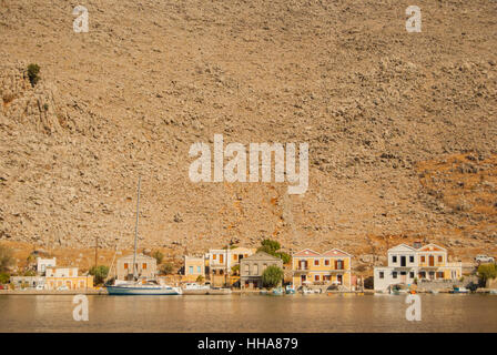 Maisons au bord de l'eau dans la baie de Pedi sur l'île de Symi en Grèce Banque D'Images