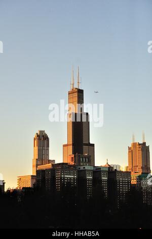 La fin de l'après-midi, coucher de soleil qui se reflète sur la Willis Tower et une partie de l'horizon de Chicago comme un aéronef à réaction passe. Chicago, Illinois, USA. Banque D'Images