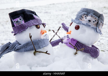 Deux bonhommes mignon habillé pour l'hiver dans les écharpes et chapeaux enlacés tant perdu des amis. Scène d'hiver avec la neige. Banque D'Images