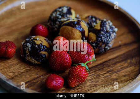 Les fraises mûres fraîchement cueillies et cookies faits maison servis sur une plaque de bois Banque D'Images