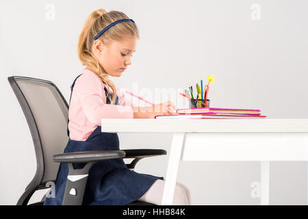 Lycéenne sérieuse assis à un bureau et à faire leurs devoirs Banque D'Images