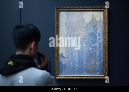 Visiteur en face de la peinture de la série de la Cathédrale de Rouen (Rouen) par Claude Monet peintre impressionniste français affiché dans le musée d'Orsay à Paris, France. Le titre complet de la peinture : la cathédrale de Rouen. Façade et Tour d'Albane. Matin Soleil. L'harmonie en blanc, 1892-1893). Banque D'Images