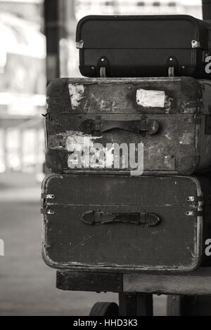 Old vintage valises empilées sur un quai de gare de train en finition sépia Banque D'Images