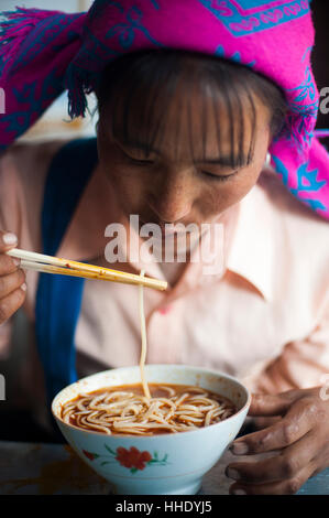 Une femme Miao mange un bol de nouilles dans la province de Yunnan, Chine Banque D'Images