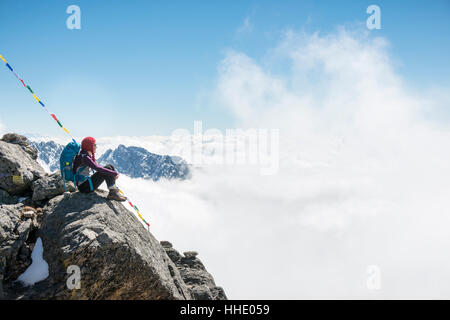 Une femme assise sous les drapeaux de prières marquant le début de la Laurebina La, le col entre le langtang région et Helmabu, Népal Banque D'Images