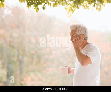 Man talking on cell phone et de boire du café sur la terrasse d'automne Banque D'Images