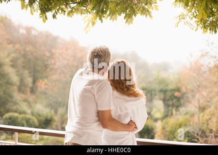 Friends hugging regarder les arbres d'automne on patio Banque D'Images