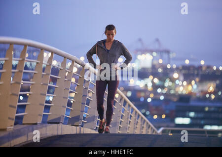 Female runner stretching jambes au repos sur la passerelle à l'aube Banque D'Images