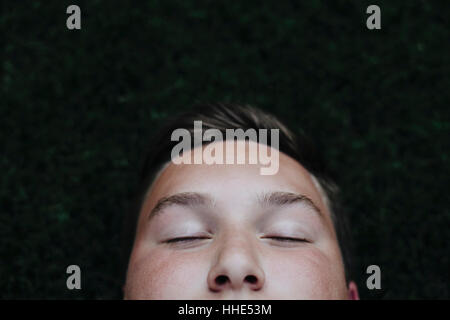 Portrait of teenage boy dormir sur l'herbe Banque D'Images