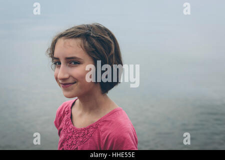 Portrait of happy onze ans, fille, à l'extérieur dans un chandail rose sourire en travers en appareil photo. Banque D'Images