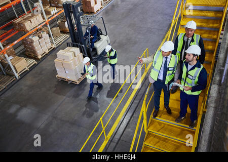 Chariot élévateur à fourche, les gestionnaires et les travailleurs en parlant de l'entrepôt de distribution Banque D'Images