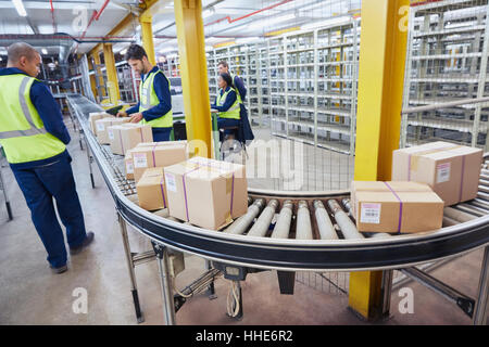 Le traitement des travailleurs des boîtes en carton sur la courroie du convoyeur en entrepôt de distribution Banque D'Images