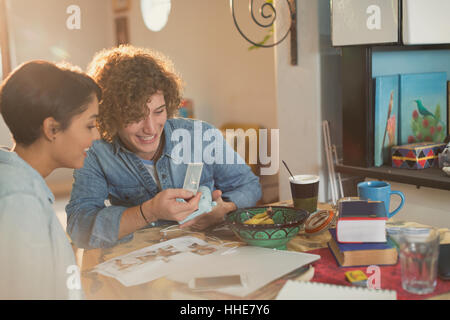 Jeune couple à la recherche de photos à l'instant à table Banque D'Images