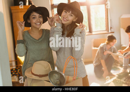 Portrait de jeunes femmes essayant d'amis sur des chapeaux en déménagement vacances Banque D'Images