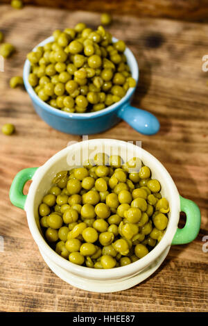 Etuve réfrigérée et les pois verts prêt à manger. Frais et doux au goût. Ici dans deux pots en fonte émaillée sur planche à découper en bois. Banque D'Images