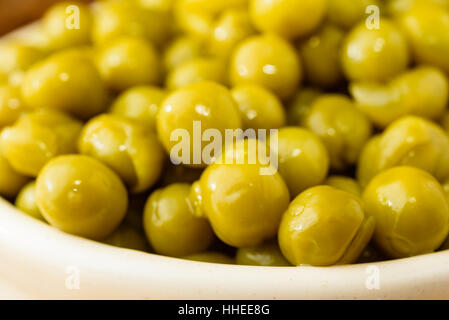 Etuve réfrigérée et les pois verts prêt à manger. Frais et doux au goût. Ici close up dans un pot en fonte émaillée beige. Banque D'Images