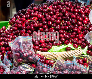Beaucoup de cerises rouges mûres dans des sacs au marché intérieur Banque D'Images