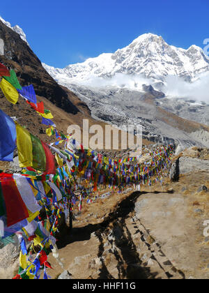 Annapurna Sud et les drapeaux de prières de l'Ian Clough/Cesar Payre Bell culte au camp de base de l'Annapurna (ABC) Sanctuaire de l'Annapurna. Banque D'Images