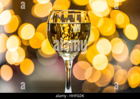 Un verre de vin blanc Pinot gris avec des lumières scintillantes dans l'arrière-plan Banque D'Images